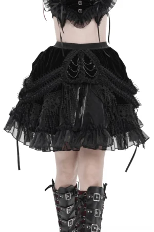 Black velvet gothic skirt with layered lace and chain details, front view on model with white background