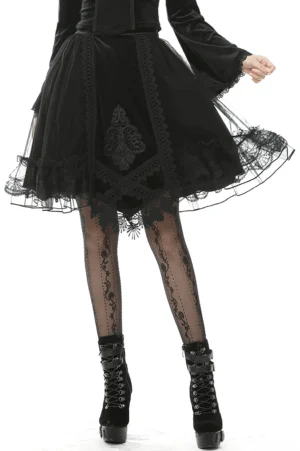 Black velvet gothic skirt with mesh overlay and embroidered lace trim - front three-quarter view on model