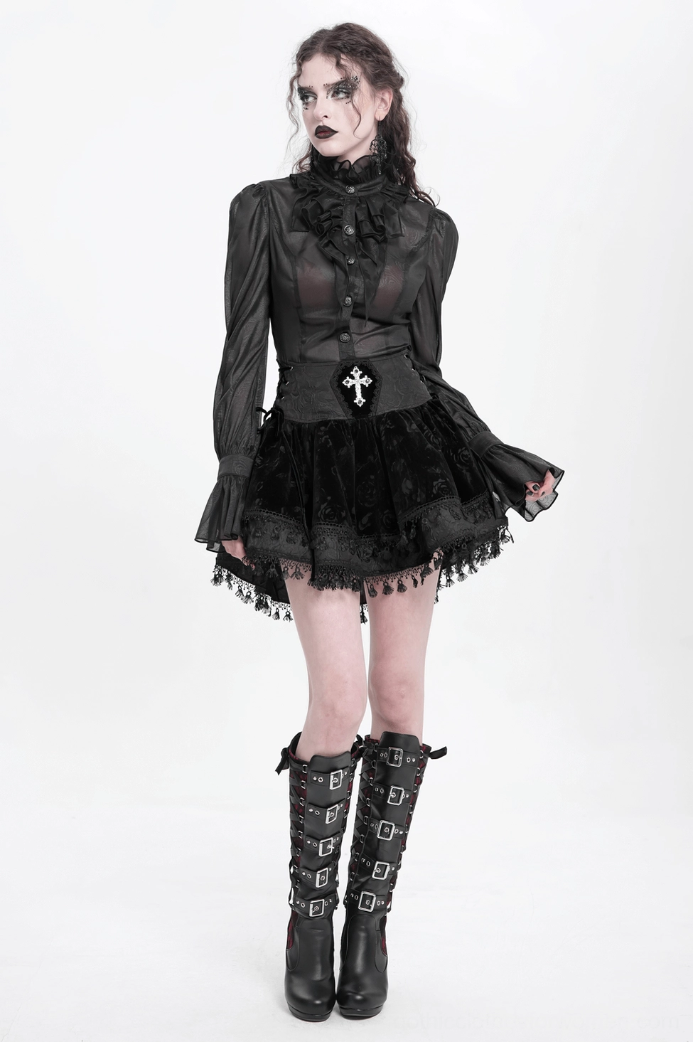 Black gothic velvet mini skirt showing structured silhouette, embroidered cross decoration, lace-up corset waist, and ruffled tassel hem detail