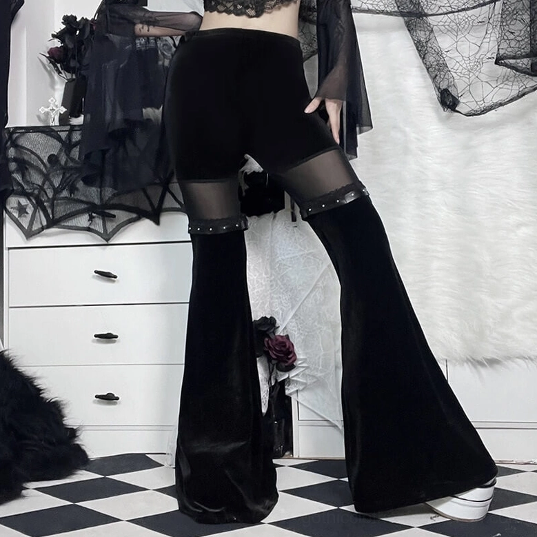 Side-back angle view of black velvet flare pants showing mesh inserts, studded details and flared leg design