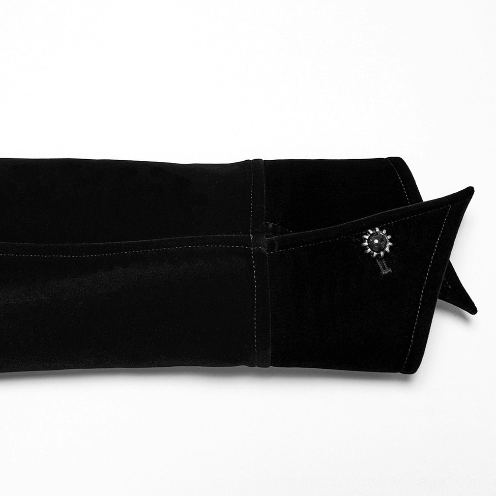 Close-up of black velvet jacket cuff with decorative gemstone metal buckle detail