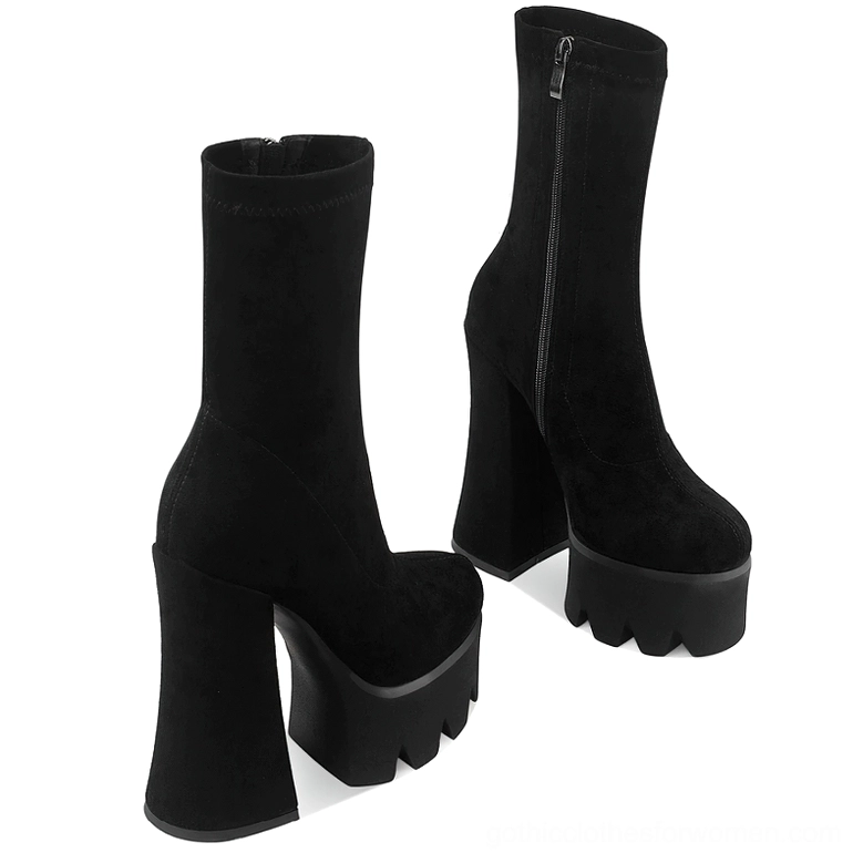 Black platform ankle boots with side zipper closure, angled front view showing suede texture and geometric sole design
