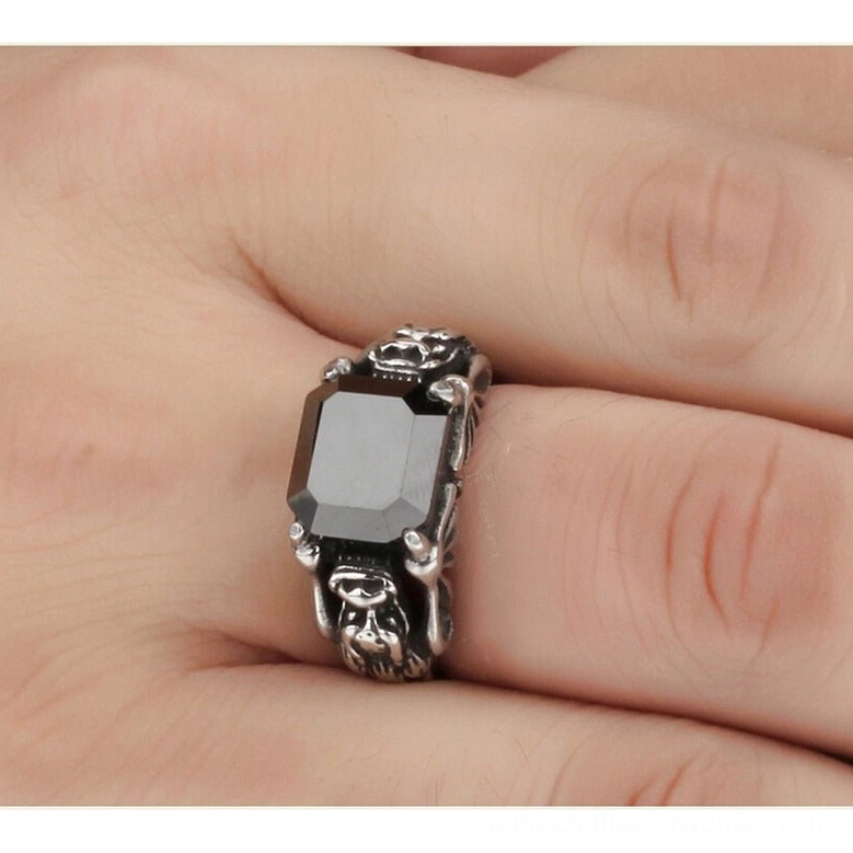 Black zircon gothic ring worn on finger showing side profile, square grey-black gemstone, skull carvings, and 13mm stainless steel band width