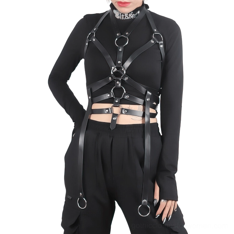 Black synthetic leather bondage chest harness with metal rings and adjustable straps worn over fitted long-sleeve crop top on model with tattooed arms