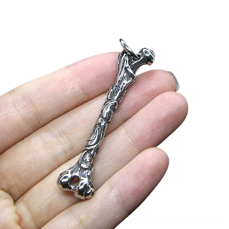 Carved bone gothic pendant held in hand displaying ornate metal detailing and side profile