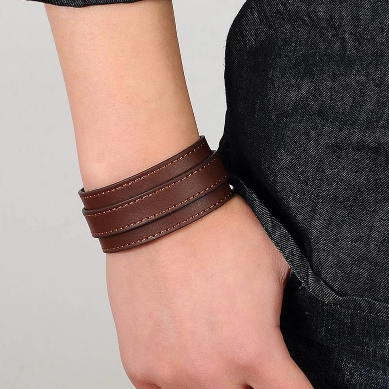 Brown gothic leather wristband worn on model wrist, close-up side view demonstrating actual size and comfortable adjustable fit