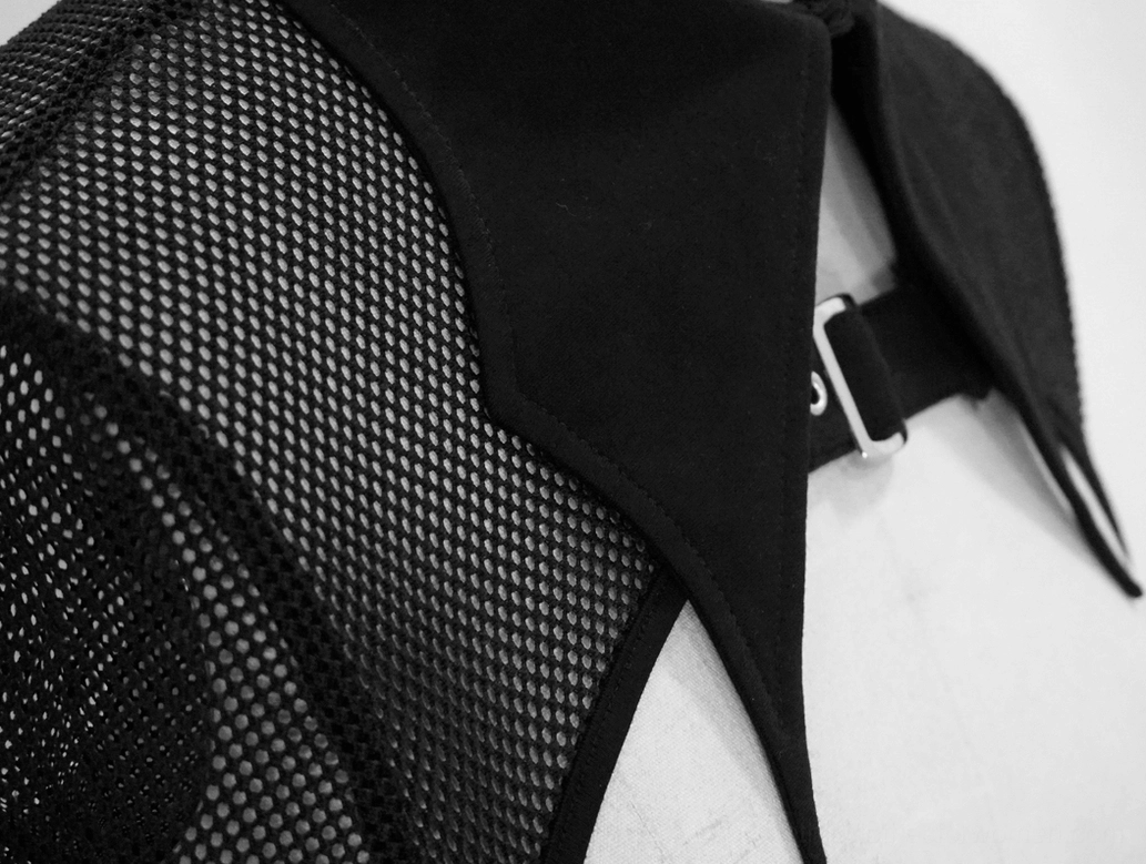 Close-up of black mesh fabric and silver leather buckle strap on gothic crop top