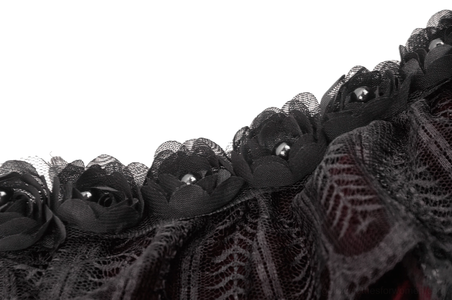 Macro close-up of black rose appliqué with sheer lace texture on burgundy bolero