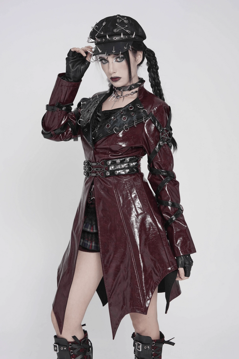 Model wearing burgundy gothic harness coat showcasing patent leather finish and dramatic silhouette in studio lighting