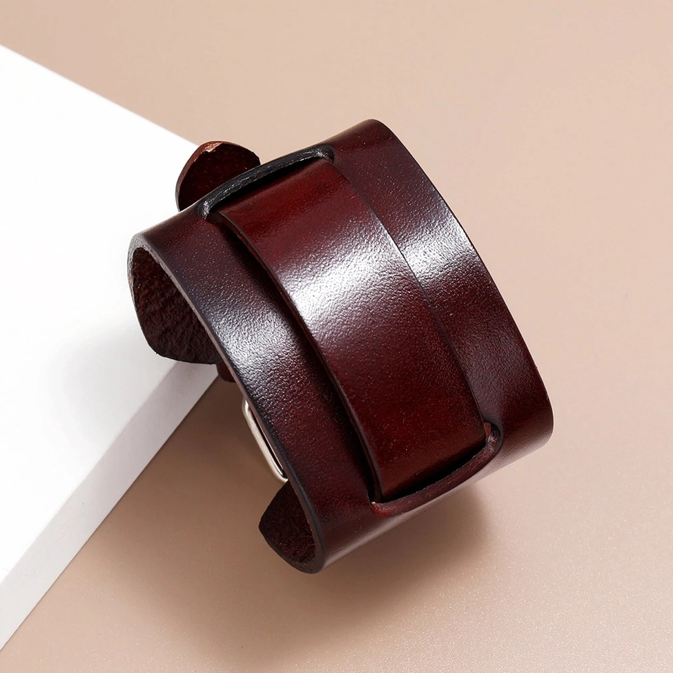 Burgundy leather gothic cuff bracelet with polished finish, 3/4 overhead view on warm-toned surface