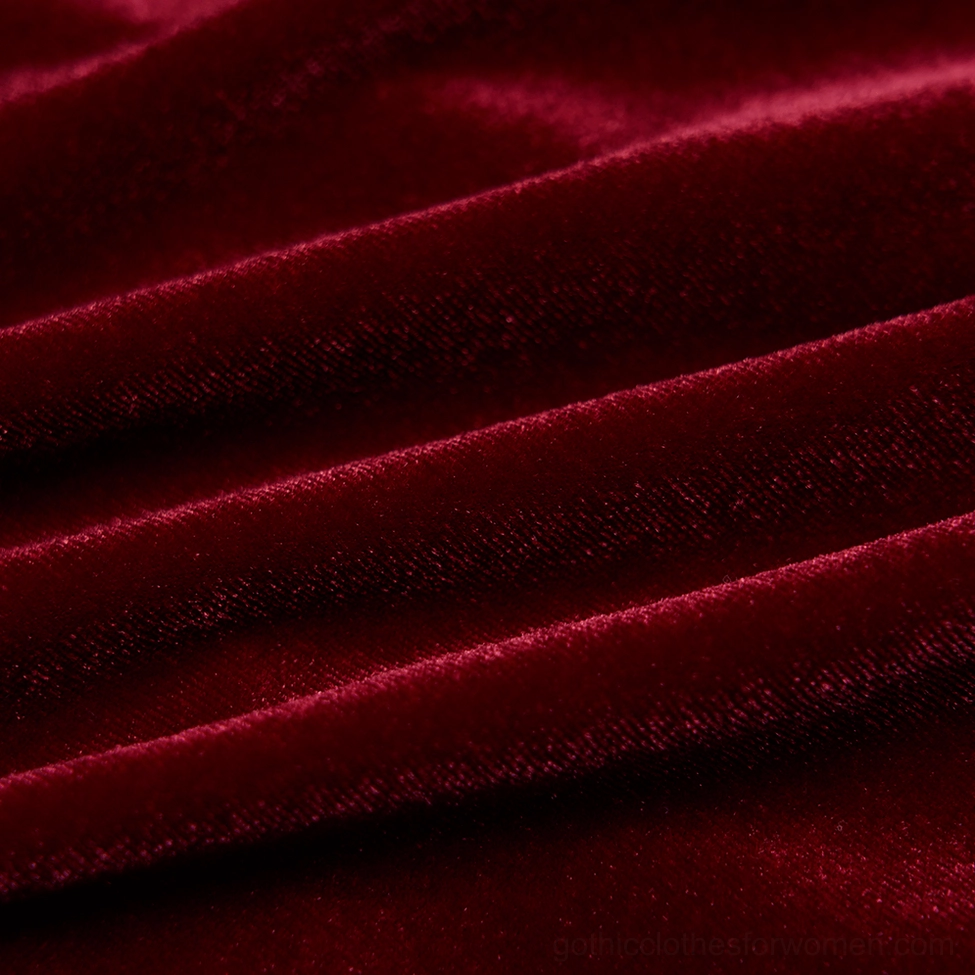 Close-up texture of burgundy red soft velvet fabric showing depth and rich color of gothic dress material