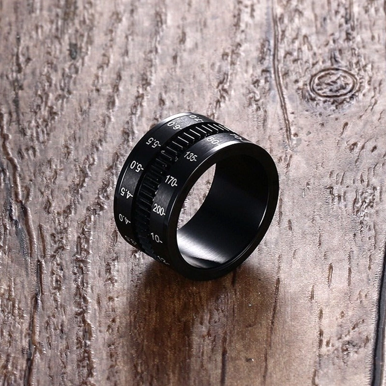 Camera lens ring side profile showcasing engraved focal length scales on wooden surface gothic aesthetic