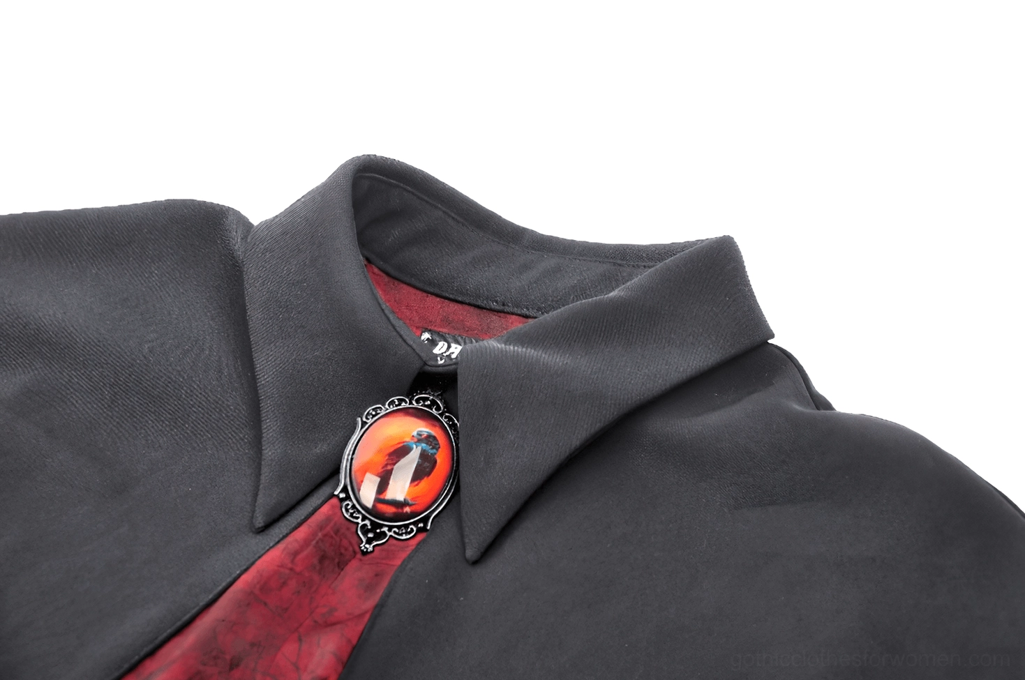 Close-up detail of vampire cape collar showing enamel jeweled brooch clasp, high standing collar structure, and red patterned inner fabric