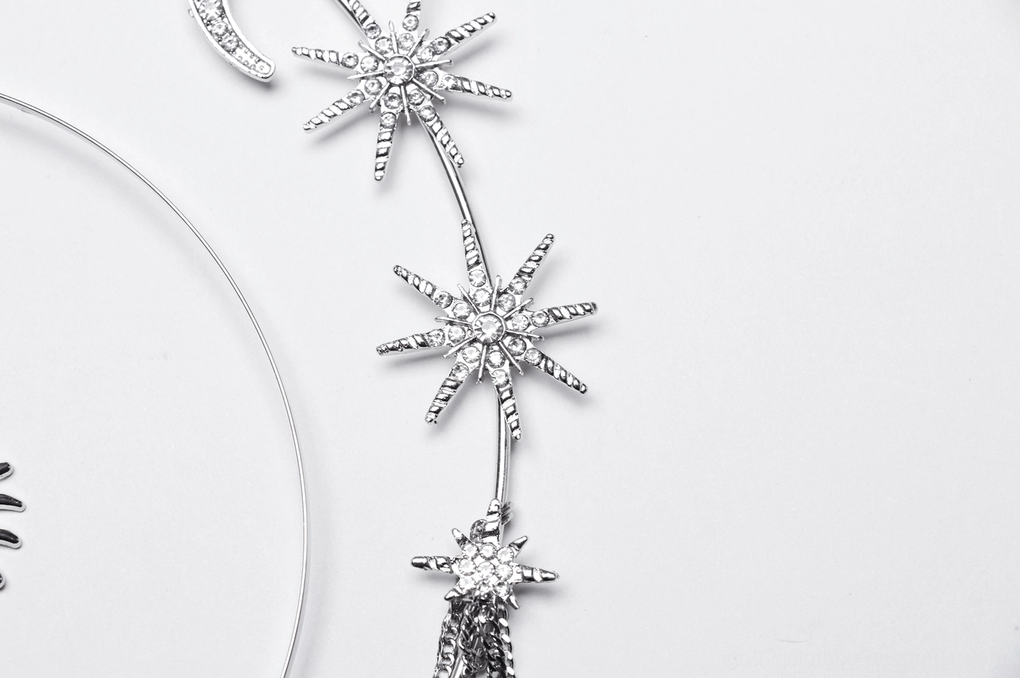 Celestial gothic crown trim detail close-up - crystal-encrusted star charms and thin silver metal wire frame structure