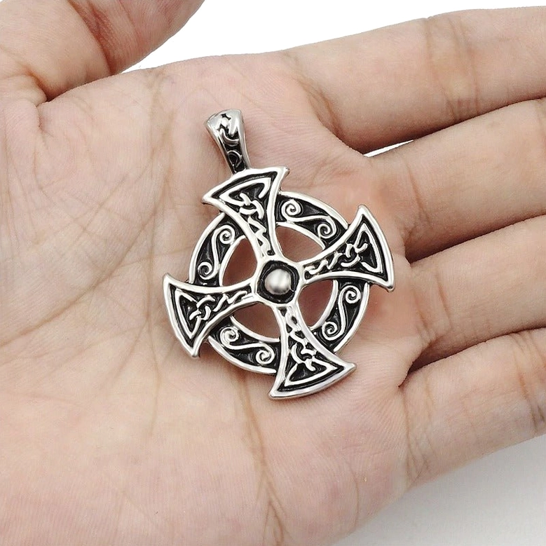 Celtic solar cross pendant held in human palm, demonstrating the compact handheld size and authentic carved Celtic knot-work texture, overhead perspective