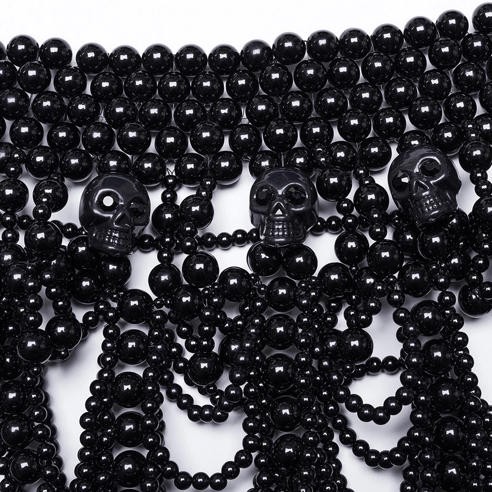Close-up detail of black pearl and resin skull decoration showing stone-encrusted focal point and pearl strand quality