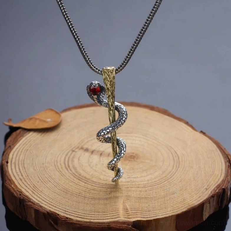 Cobra pendant necklace with red gem displayed on wooden stump with antiqued chain