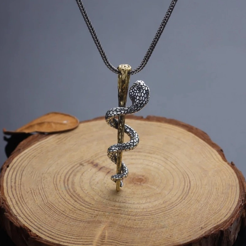 Antiqued silver and gold cobra pendant on wooden surface showing serpent craftsmanship
