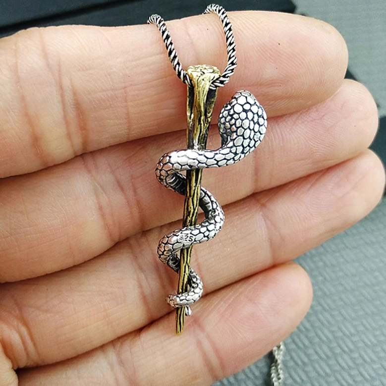 Sterling silver cobra pendant in hand showing scaled snake design without gemstone