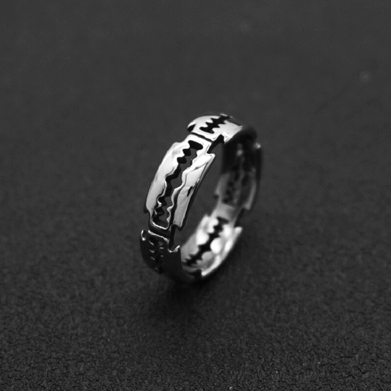 Compact razor blade ring with sawtooth design, stainless steel silver metal, side close-up on dark solid background