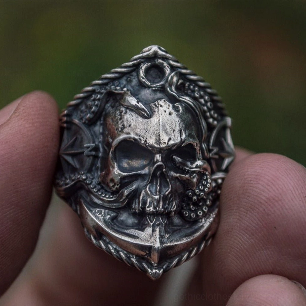 Compass skull anchor ring with weathered silver finish held in hand against natural outdoor background