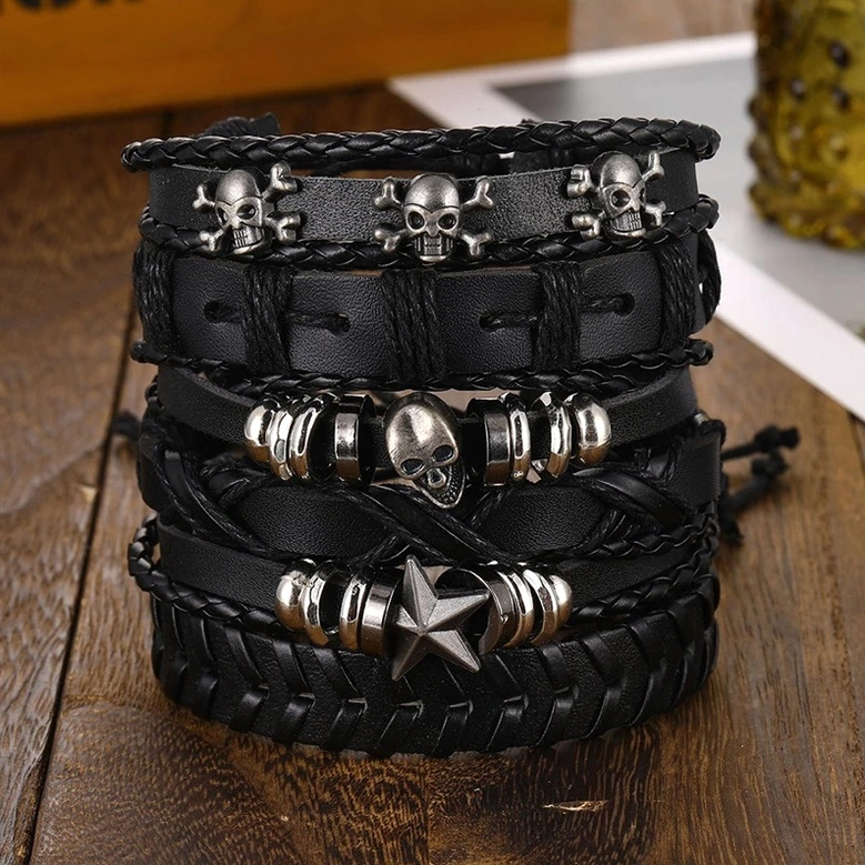 Complete six-piece black gothic leather bracelet collection stacked together on wooden tabletop showing full set with skull, star, braided leather and metal accents