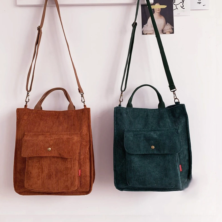 Camel and dark green corduroy gothic tote bags displayed together on wall, showing color range and front snap pocket details