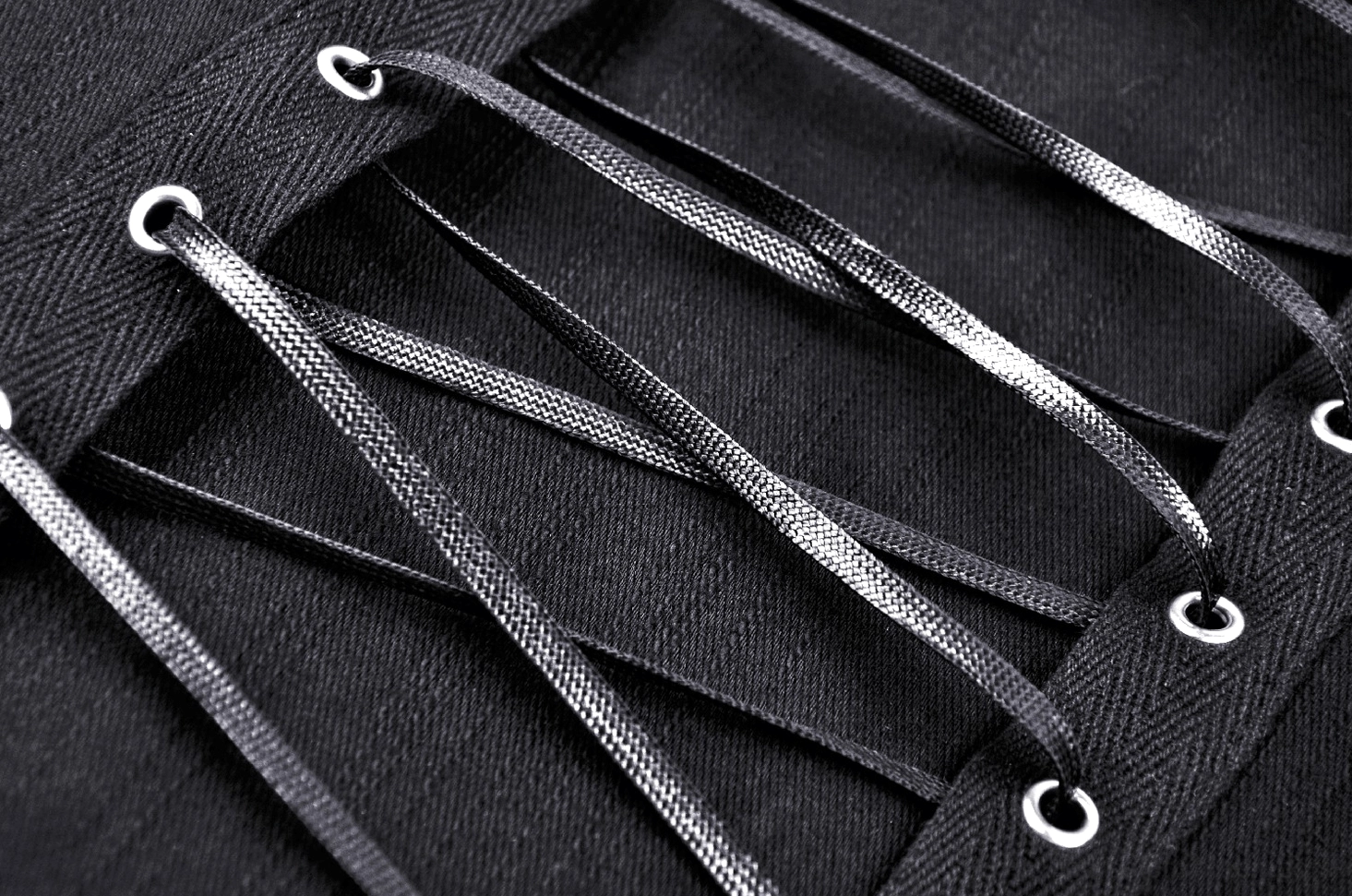 Detailed view of shiny metallic lace-up cords and fabric eyelets on corset closure