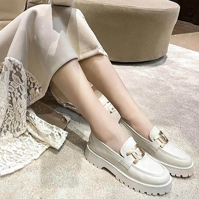 Cream gothic platform loafers styled with lace skirt on lower leg, side view showcasing smooth leather upper, metallic chain decoration, and commanding chunky platform sole in casual setting