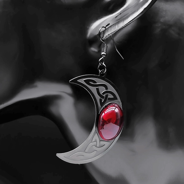 Close-up on ear model wearing silver-toned crescent moon earring with red stone, Celtic knotwork visible, worn styling