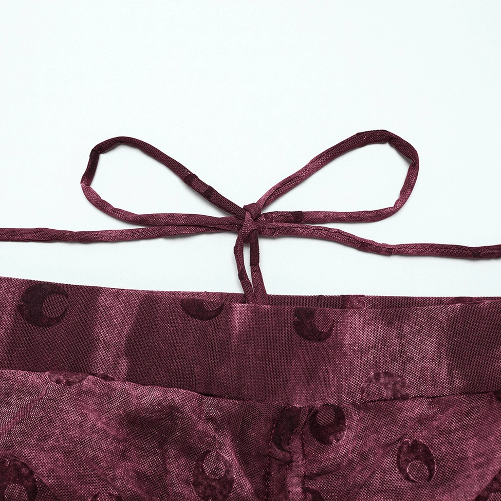Close-up detail of crescent moon flocked embroidery on sheer burgundy mesh fabric