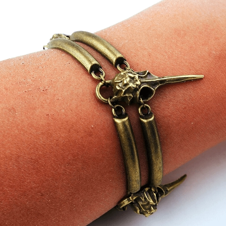 Crow skull layered bracelet on human wrist, side profile featuring central bird skull and double metal band design