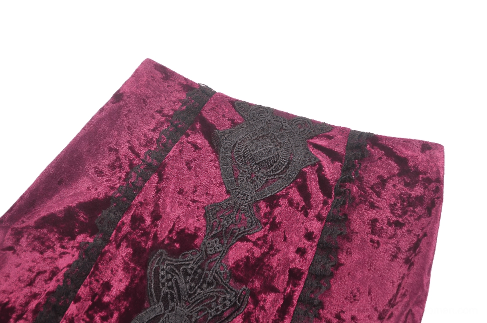 Close-up texture detail of crushed wine red velvet with gothic embroidered trim and brocade pattern