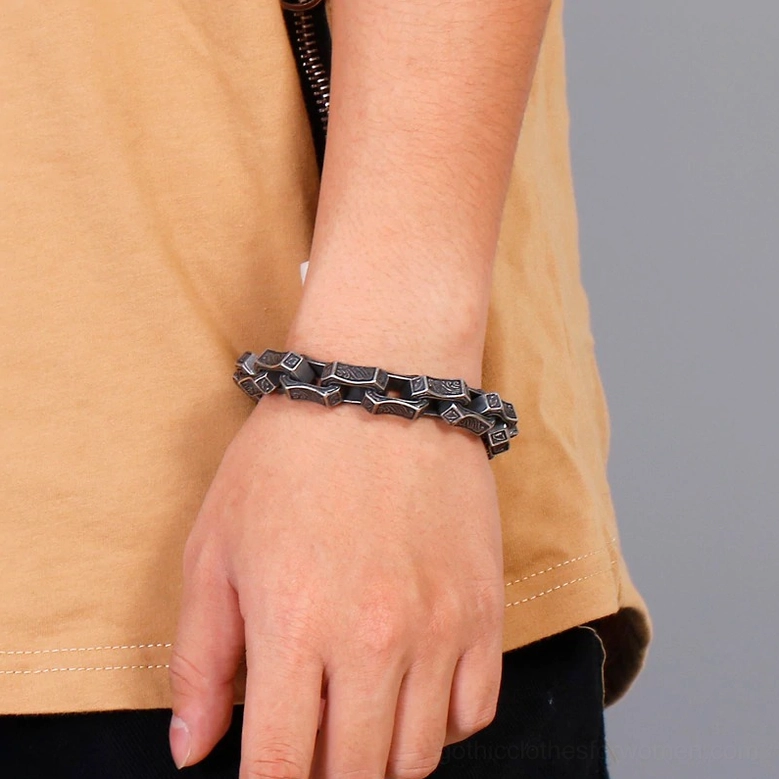 Dark antique silver gothic engraved bracelet worn on male wrist close-up side view casual styling