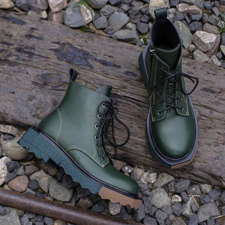 Dark green leather gothic platform ankle boots on outdoor wooden surface, lace-up and zipper closure system visible, lifestyle shot