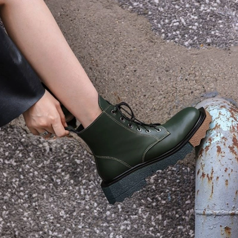Close-up side profile of dark green genuine leather gothic boots with side zipper and platform sole, outdoor industrial aesthetic