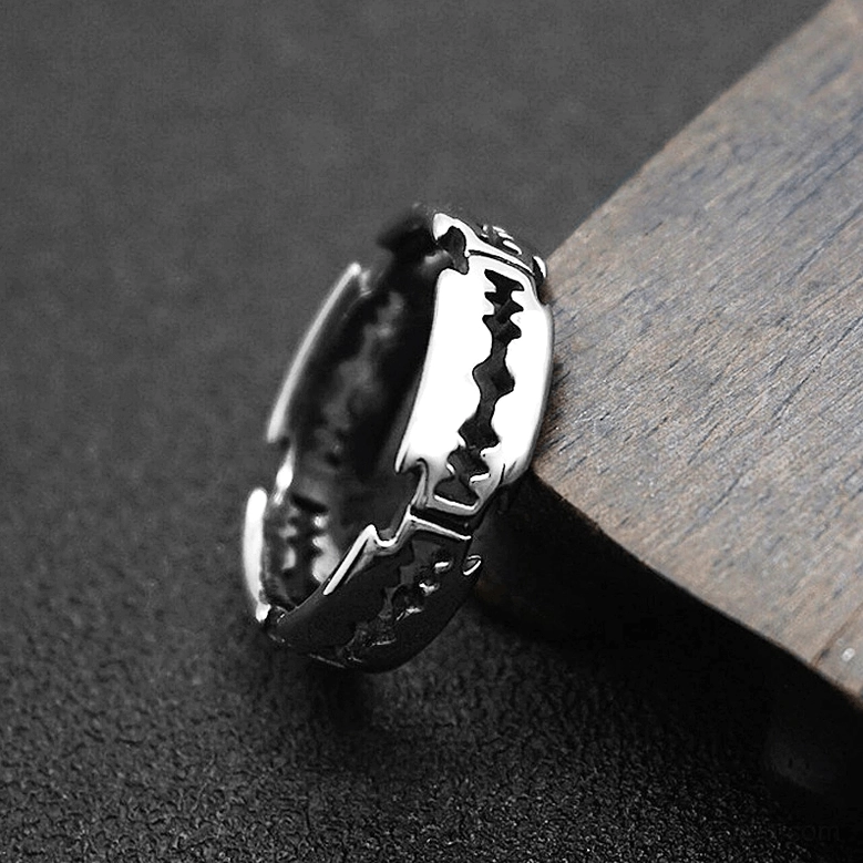 Dark silver blade ring with detailed sawtooth pattern, side close-up view on dark textured background with wood trim