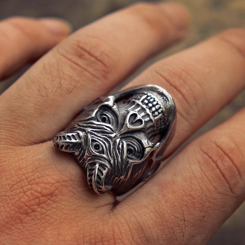 Three-eyed demon skull ring worn on male hand showing intricate facial carving and aged silver patina