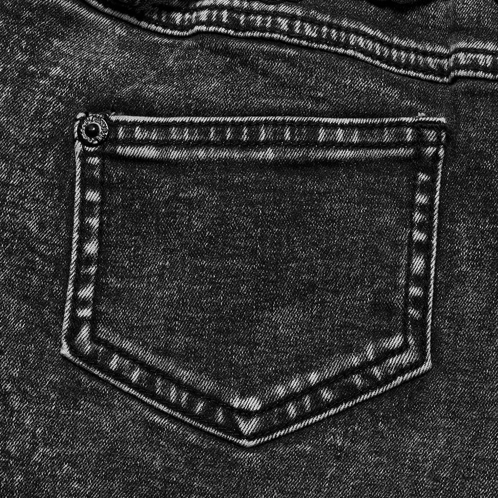 Detailed close-up of reinforced rear pocket stitching on faded black acid-washed denim with gothic aesthetic