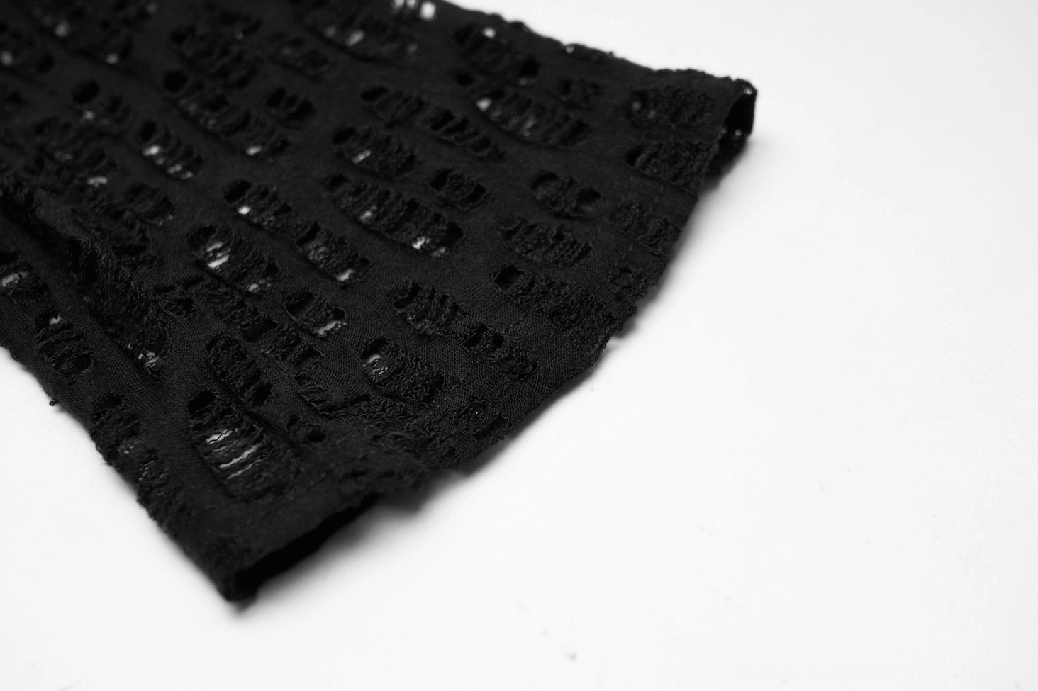 Close-up macro shot of distressed black mesh fabric texture showing frayed hollow-out detail