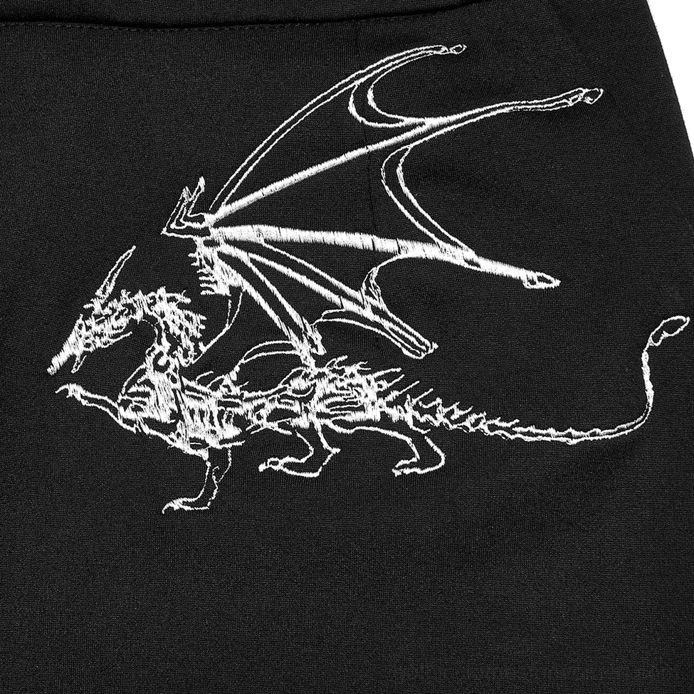 Close-up of white-thread dragon skeleton embroidery detail on black gothic fabric