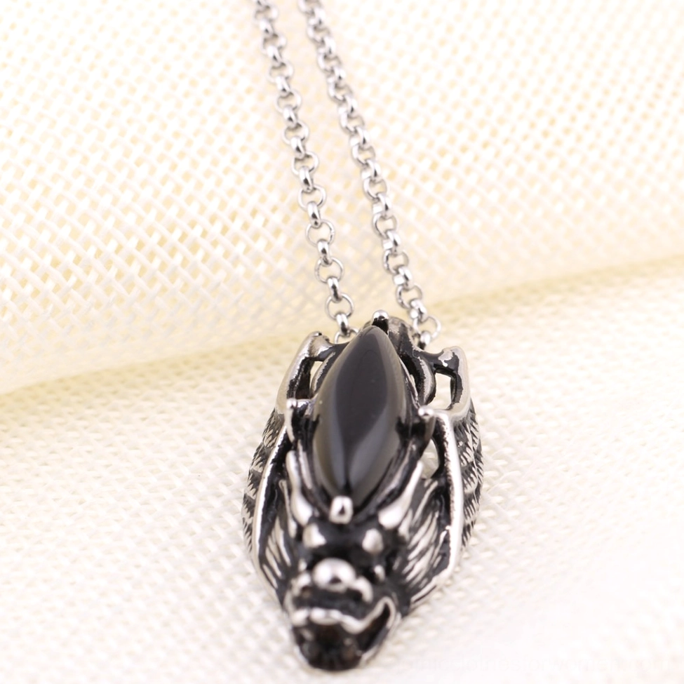 Dark silver dragon head gothic pendant with marquise stone inlay, front overhead close-up on textured background