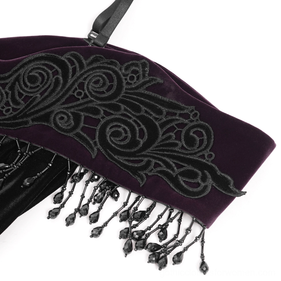 Off-shoulder dress trim close-up showing scroll embroidery and black beaded fringe decoration
