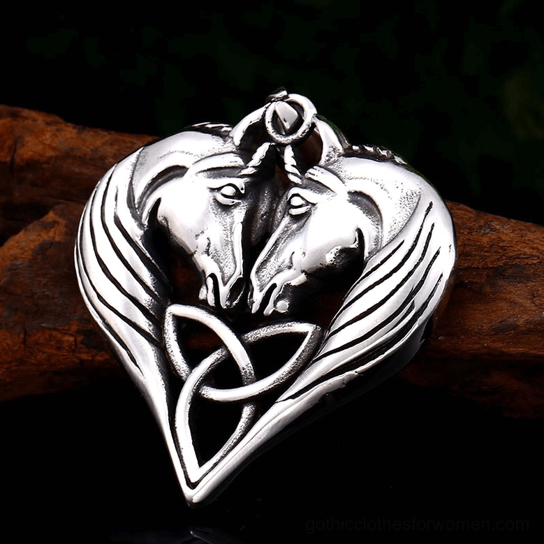 Heart pendant featuring dual horse heads with intricate Celtic knotwork on brown wooden background, close-up highlighting carved facial features and frame design