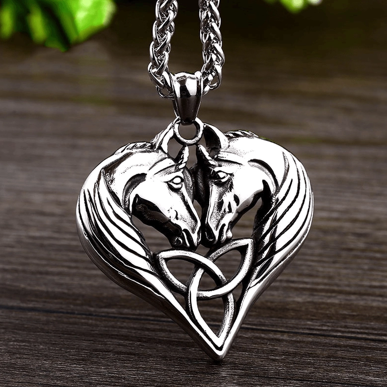 Vintage silver dual horse heart pendant with twist chain on dark wooden surface, three-quarter view showing pendant depth and rope chain details