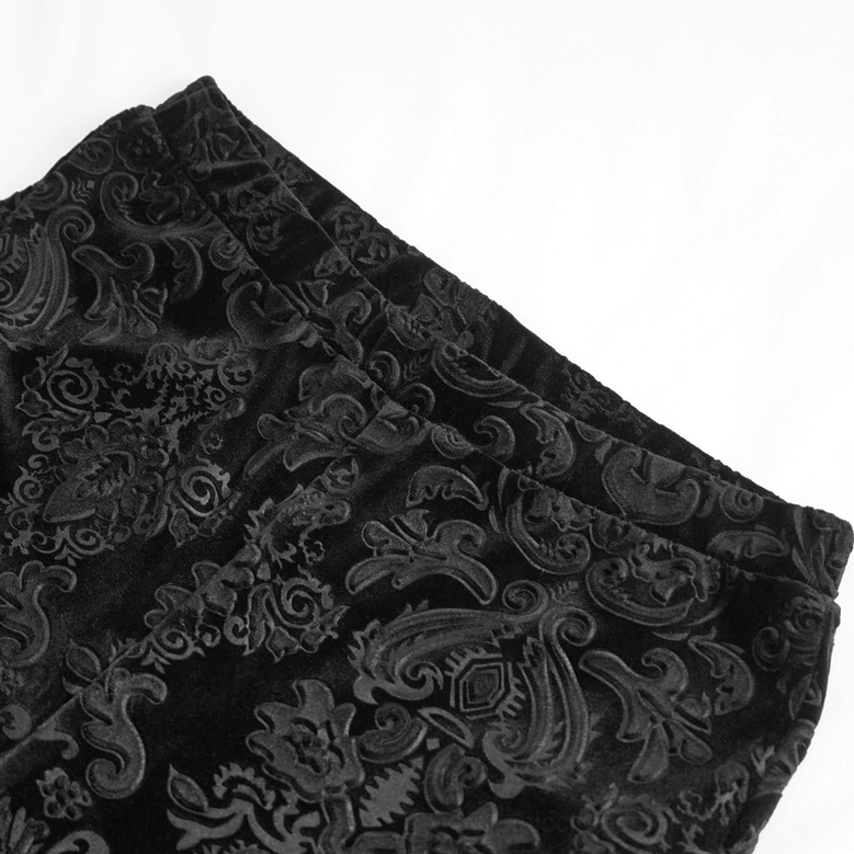Black embossed damask velvet fabric texture close-up on folded gothic flared pants, flat lay detail shot