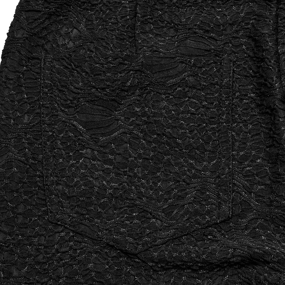 Detailed close-up of embossed skull lace fabric texture on black gothic leggings showing fine woven pattern