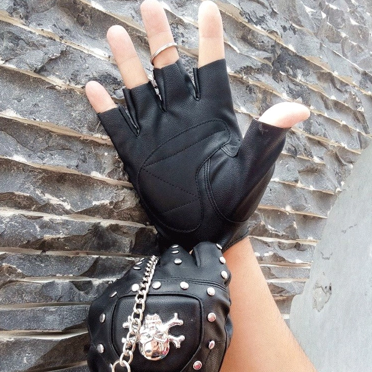 Half-finger faux leather gothic gloves featuring silver skull decoration and industrial rivets - studio shot