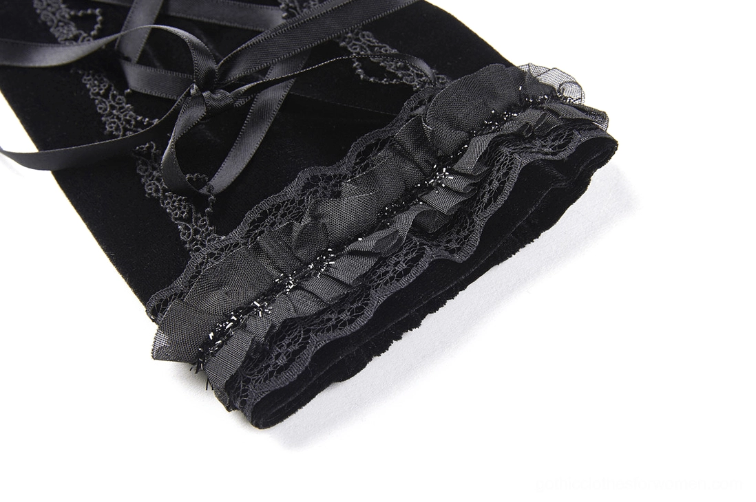 Close-up detail of black fingerless glove cuff showing ruffle lace trim, ribbon lacing detail, and rich velvet fabric texture