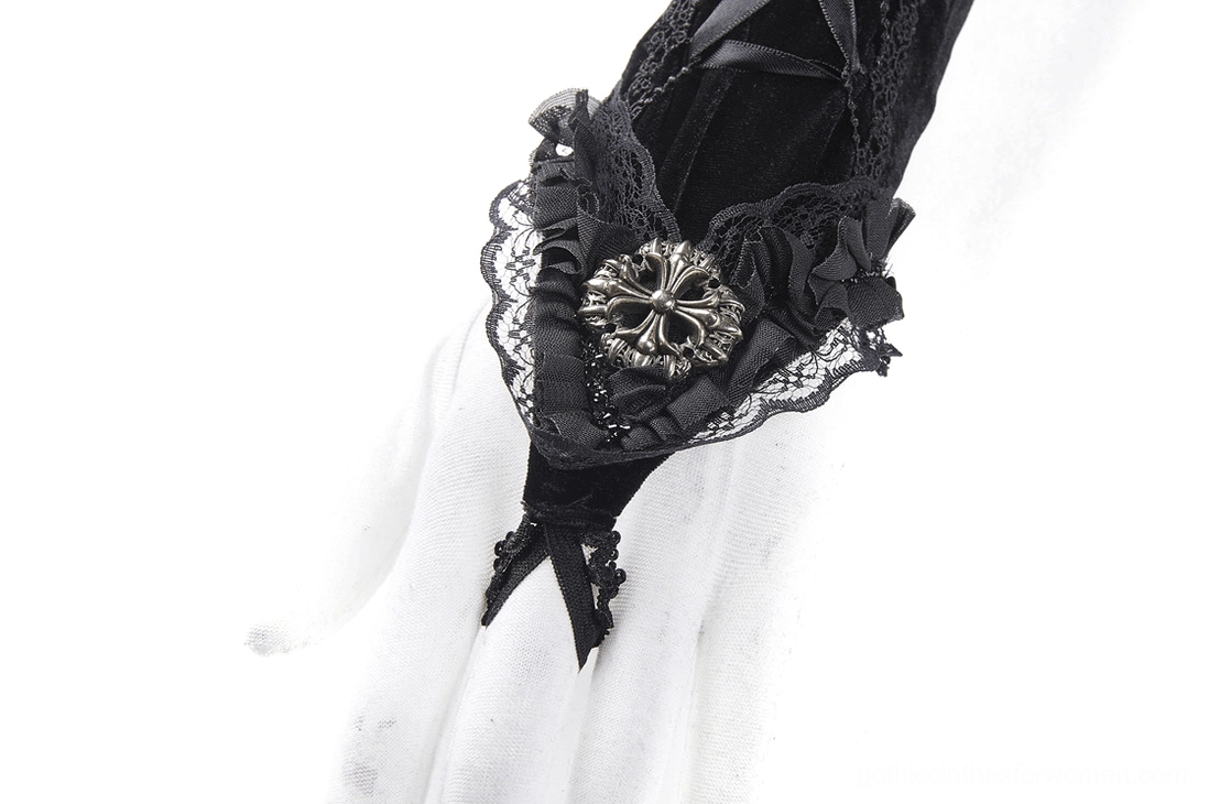 Close-up detail of black fingerless glove cuff on mannequin hand, highlighting lace ruffle trim and metal cross ornament accent
